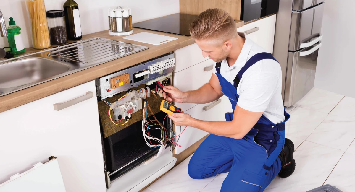 Technician testing the exposed electrical components of a dishwasher