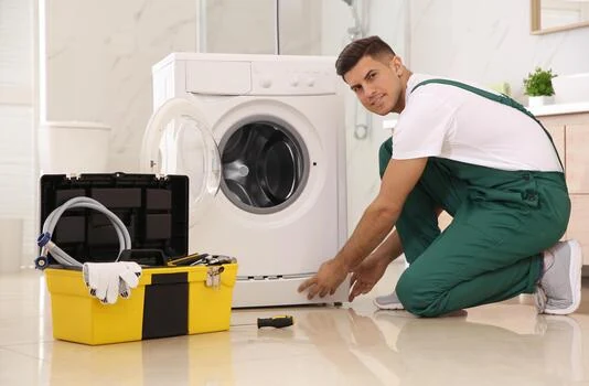 Technician beside a front-loading washing machine with a yellow toolbox